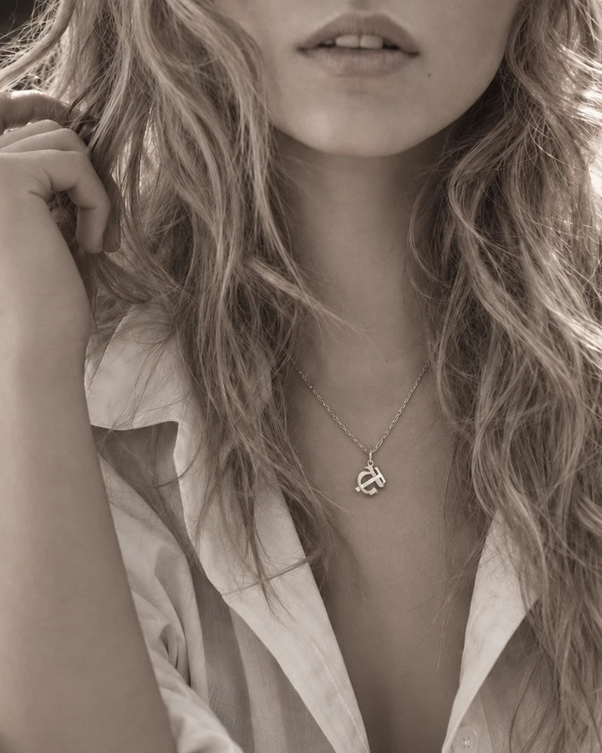 An Entwined initials pendant worn at the collarbone