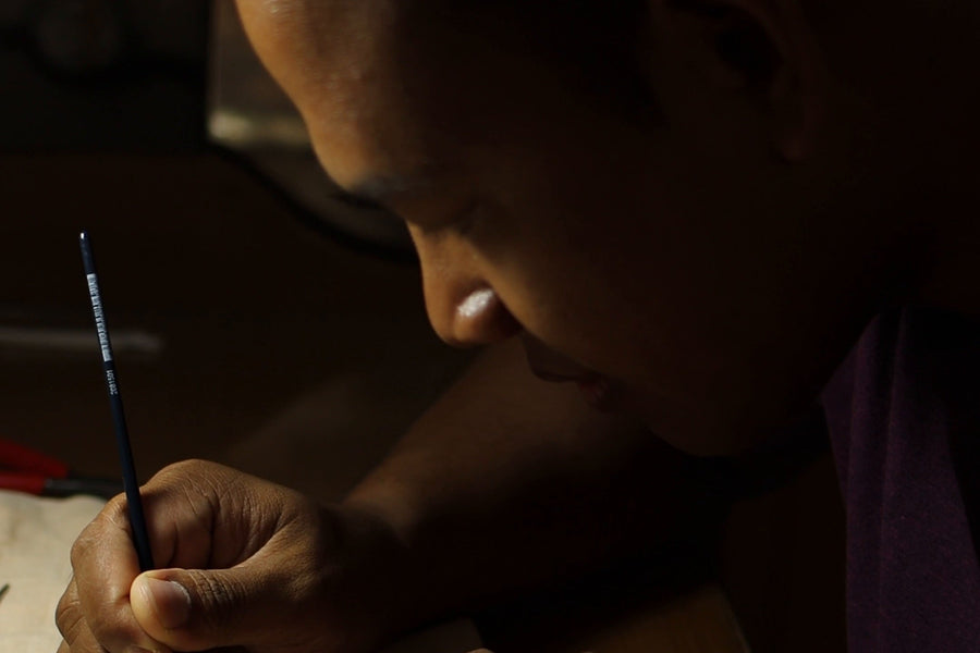 At the bench in Bali, a smith bowed over a fine brush, working on a pendant on linen