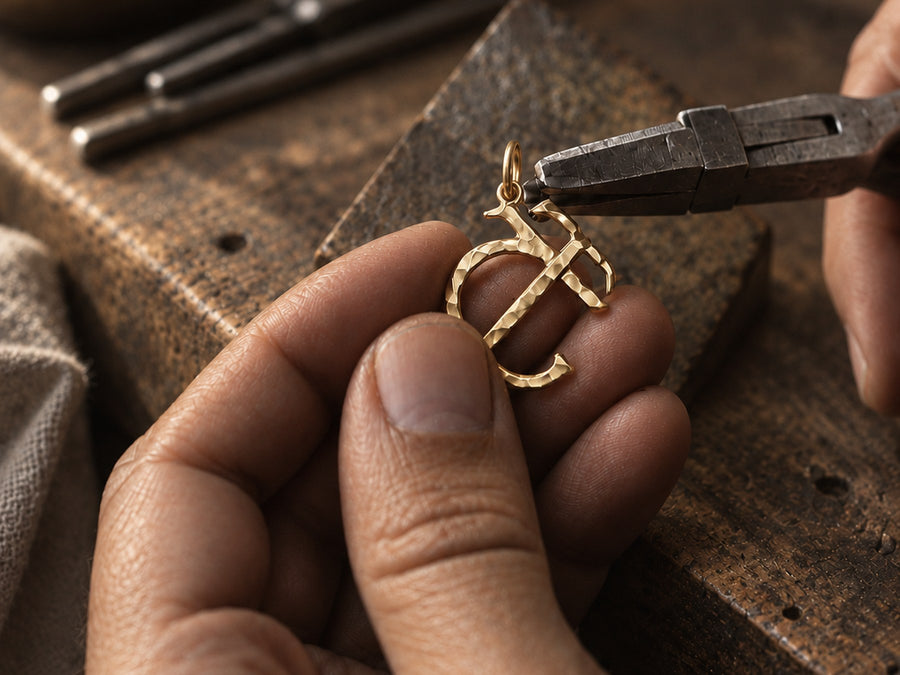 The Entwined pendant held between the silversmith’s fingers at the bench, pliers at the bail