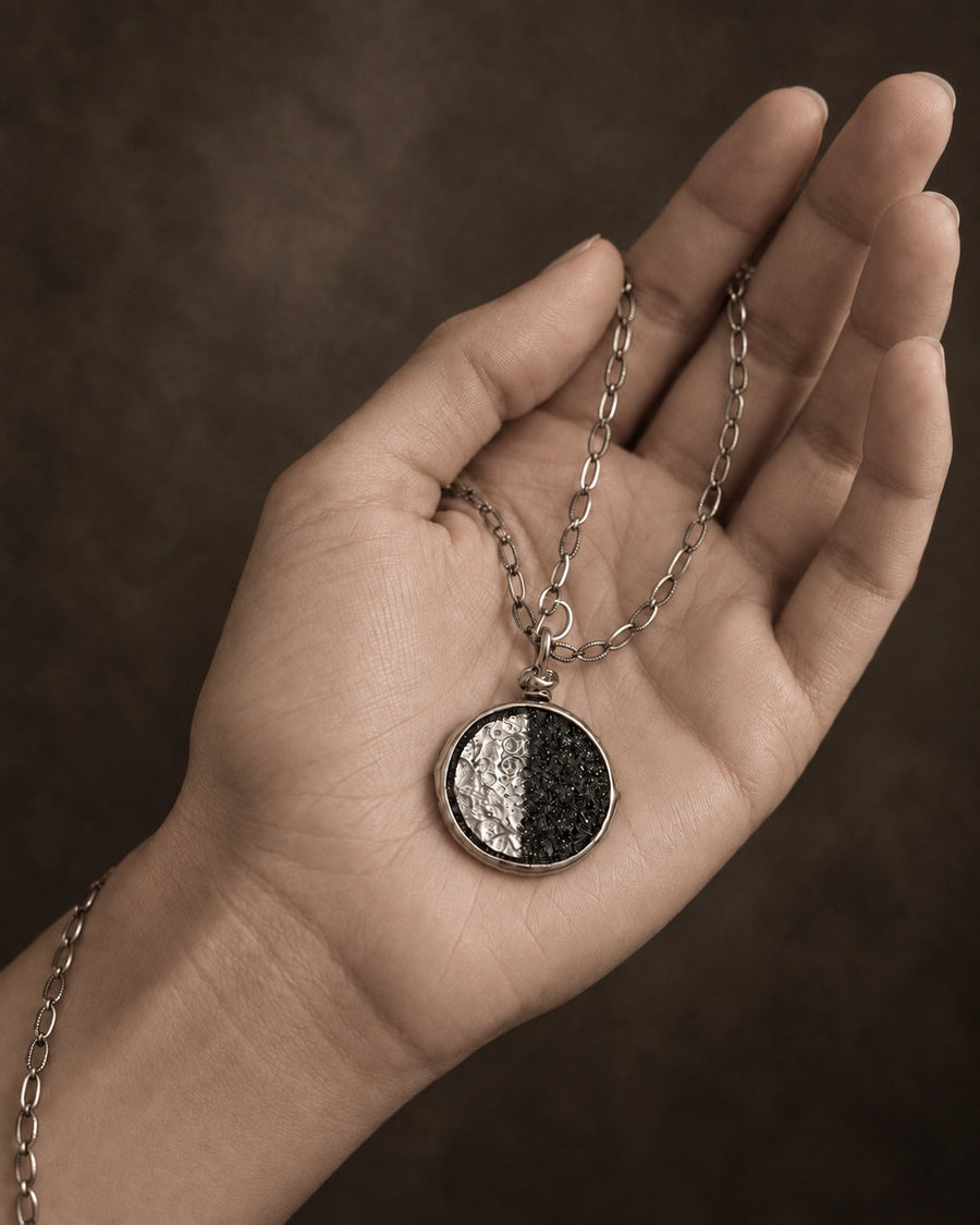 The Moon pendant held in an open palm, half its face lit